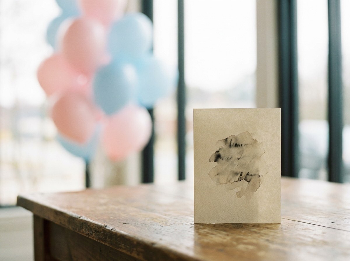 A single card standing on a pale surface with balloons far out of focus behind
